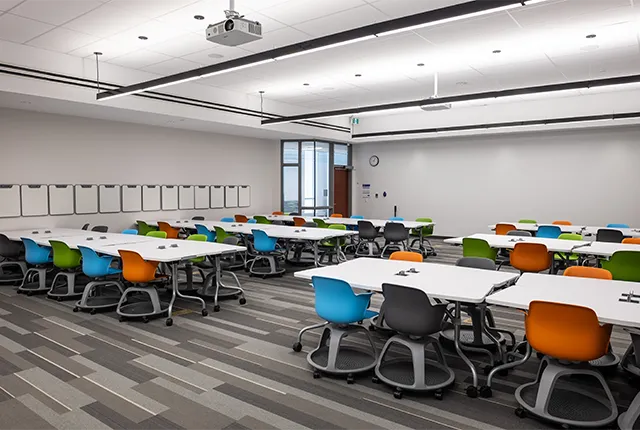 A photo of a campus classroom with colourful chairs and communal desks.