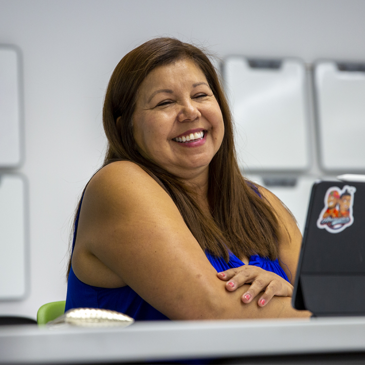 A woman laughing at desk in the indigenous student center.