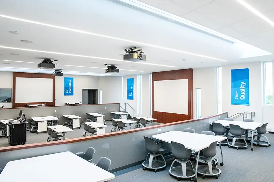 An image of the learning room with desks and projector screens.