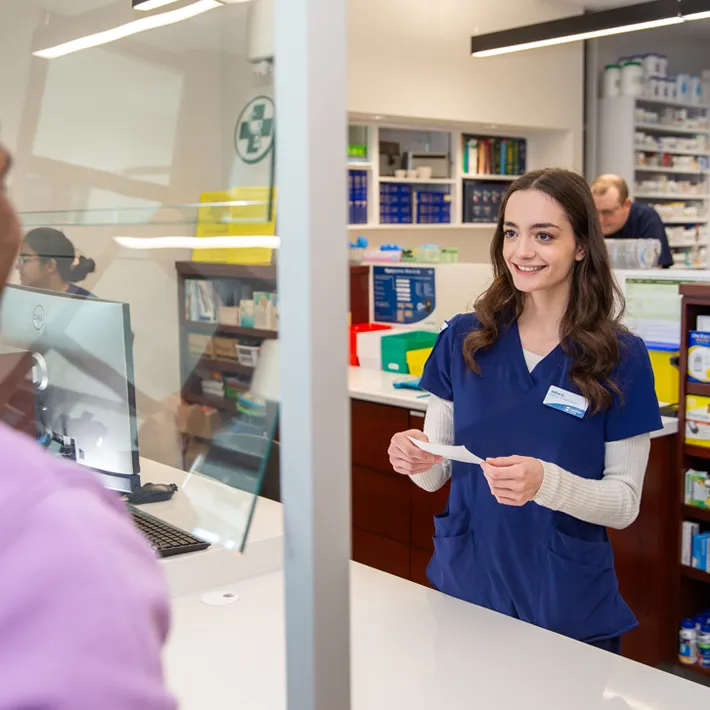 Student holding a prescription smiling at a customer