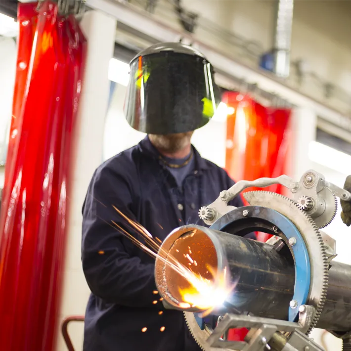 A photo of a student cutting a pipe in the steamfitter lab.