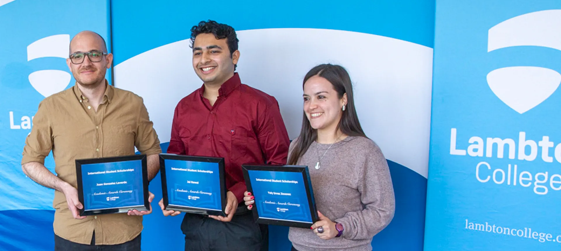 Three students holding their academic award certificate