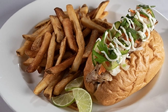 A photo of the bahn mi with a side of french fries.