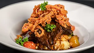 Slow roasted beef brisket au jus served with creamy Dijon mashed potatoes, blistered cherry tomatoes, crispy red onions, and pan gravy.