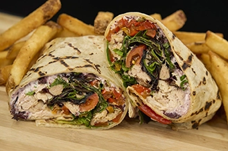 A photo of the Mediterranean Chicken Wrap with a side of french fries.