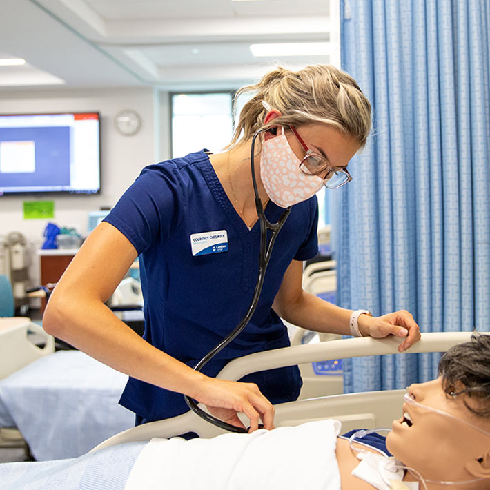 Nurse student practising on dummy patient.