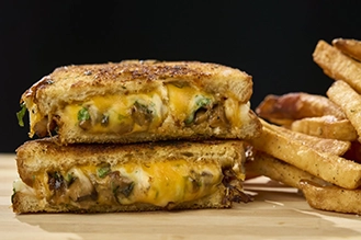 A staged photo of the truffled mushroom grilled cheese with a side of french fries.
