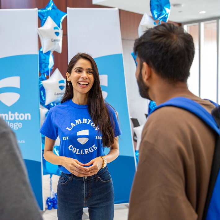 Students smailing and connecting during orientation with banners and balloons in background.