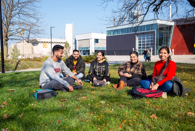 A group of students sitting in the grass on campus.