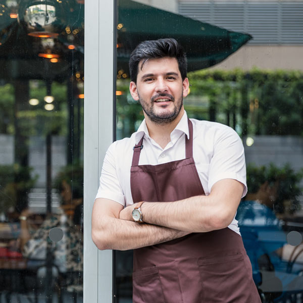 Man in apron stands outside restaurant
