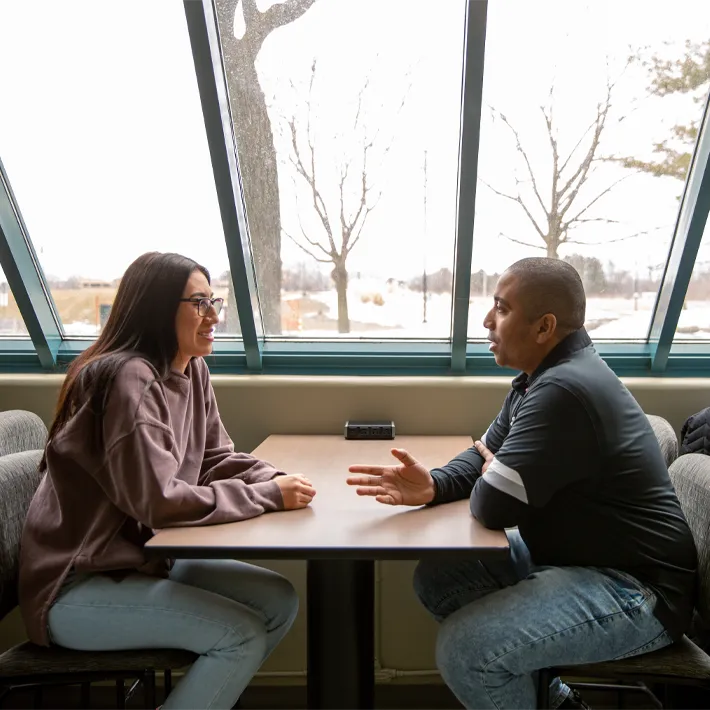 Financial aid staff member talking with student in lounge area.