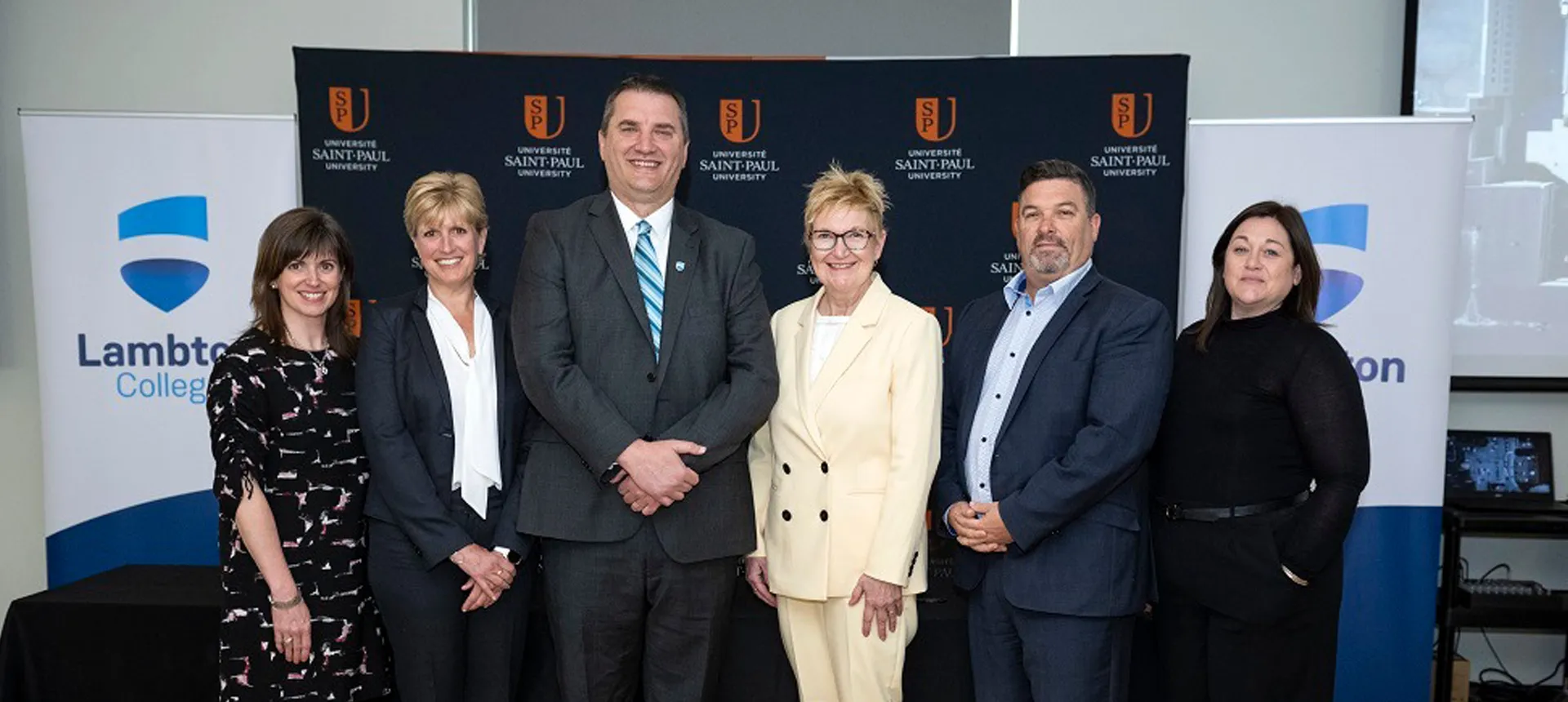 Lambton College and Saint Paul University administrative staff smiling standing together