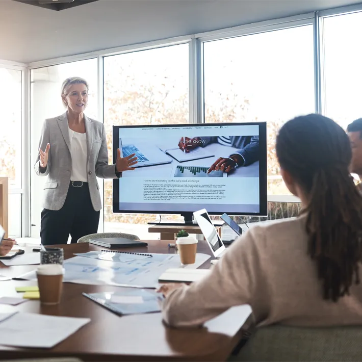 A woman presenting to a group of people in an office.