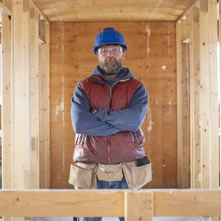 A carpenter student posing for photo in half built house.