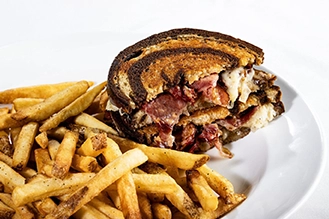 A photo of the Reuben sandwich with a side of french fries.