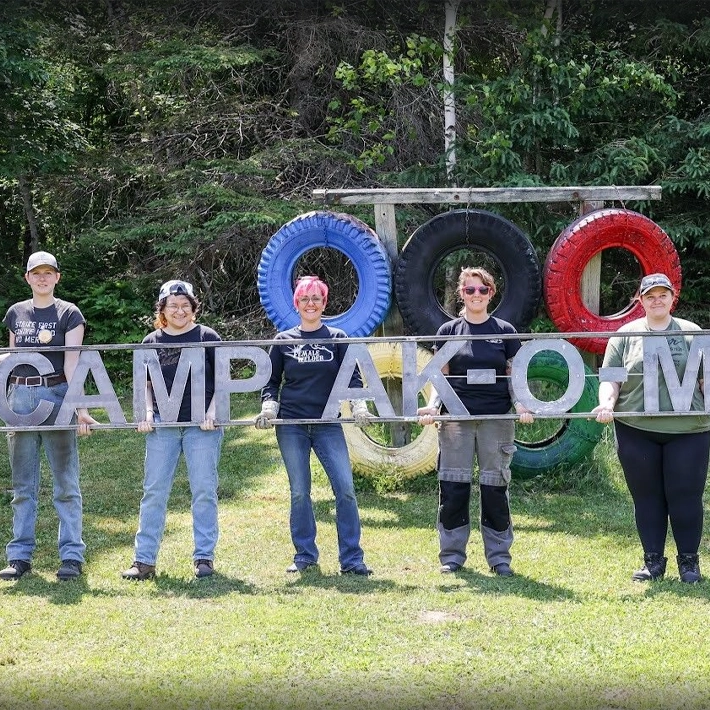students-women in trades holding a sign together outside-technology-710x710 Women standing from a sign posing for photo outside.