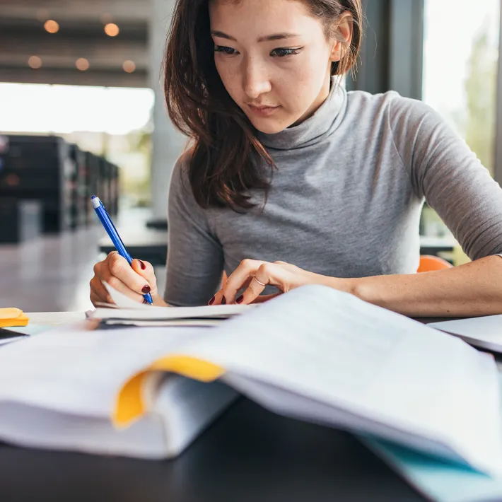 Women in office writing notes as she researches.