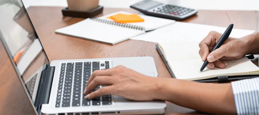 Student studing at desk with notepads, computer and calculator.