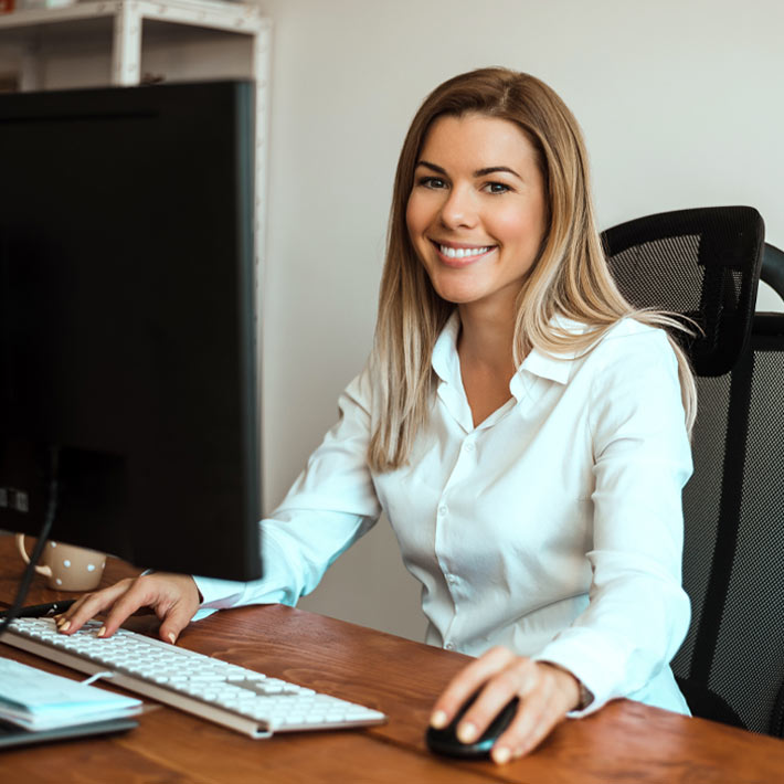 A young woman sitting at a desk using computer.