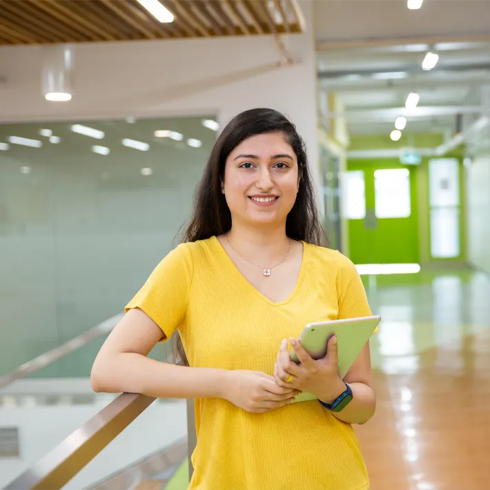 Cestar-Lifestyles-international-student A student wearing a yellow t shirt and holding ipad posing for a photo on campus.