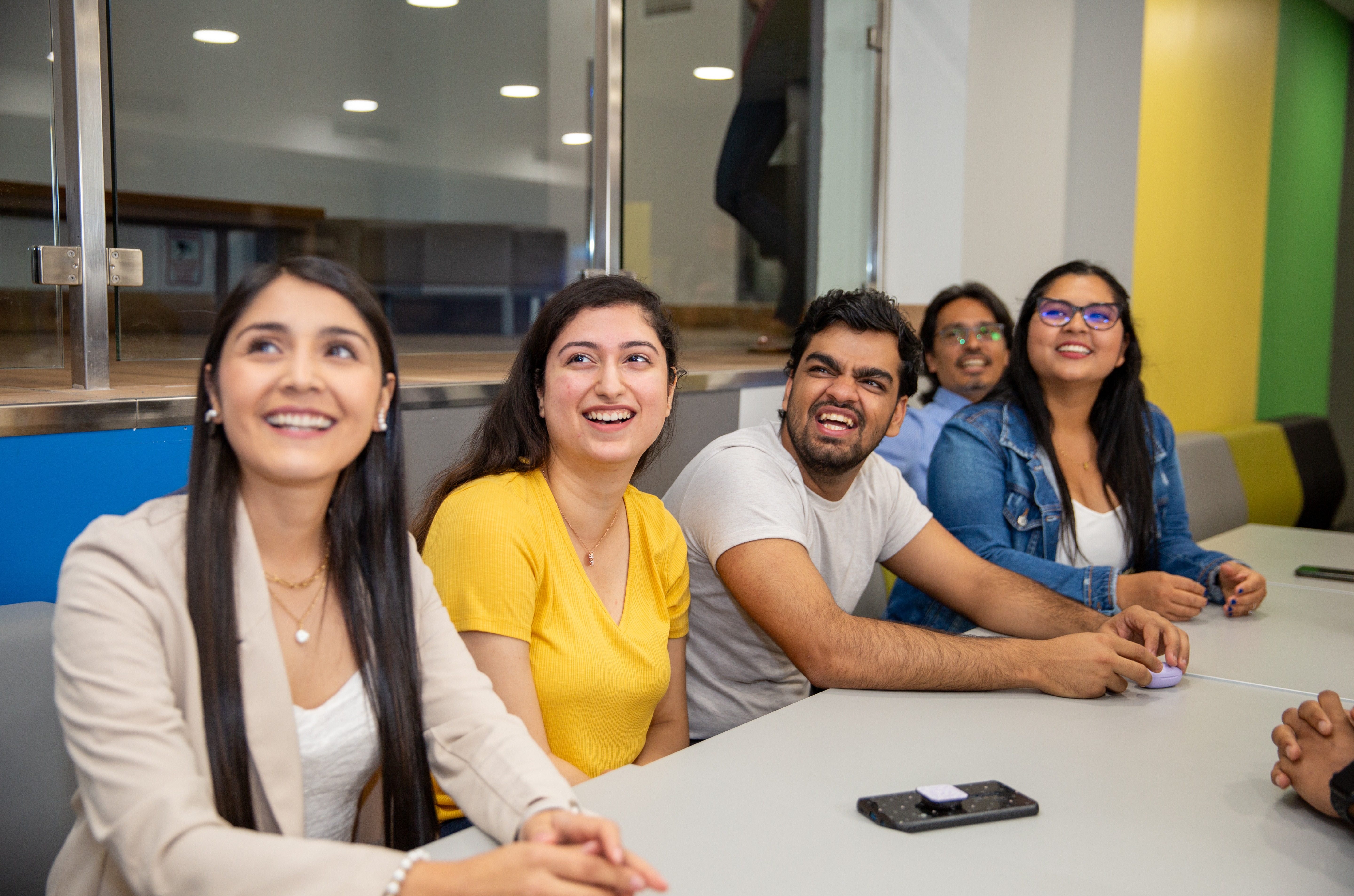 A group of international students sitting on benches smiling towards camera and laughing.