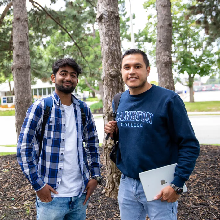 Cestar-Lifestyles-international-students Two international students posing for photo outside with trees and road in background.