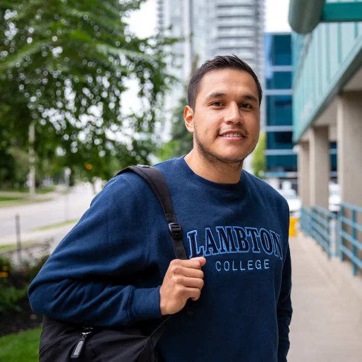 Cestar-Lifestyles-international-toronto-student A photo of a student wearing a packback and blue sweater standing outside of campus.