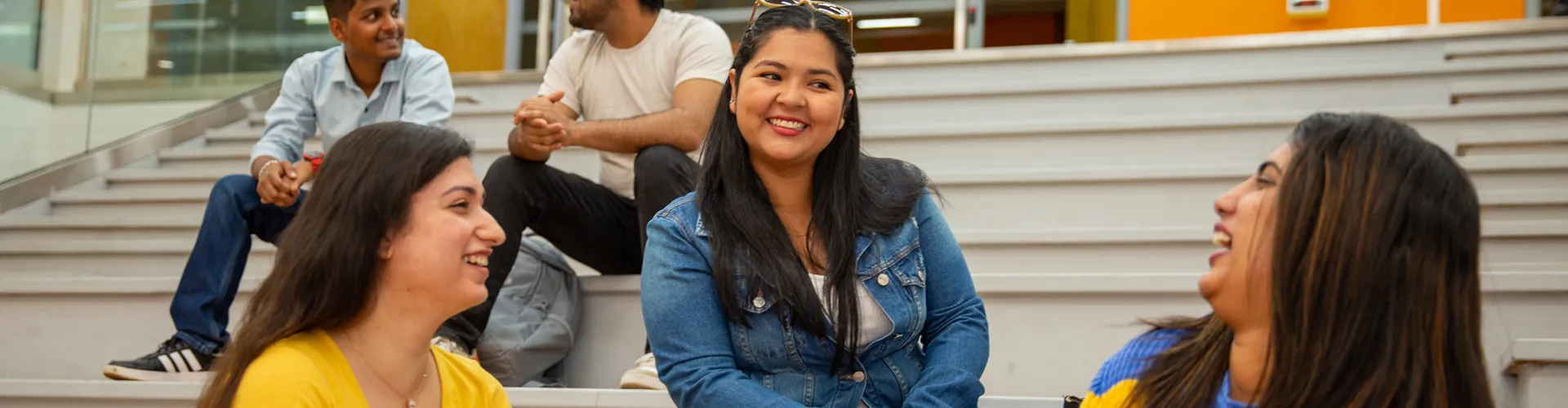 A lifestyle photo of students sitting together on campus laughing and smiling.