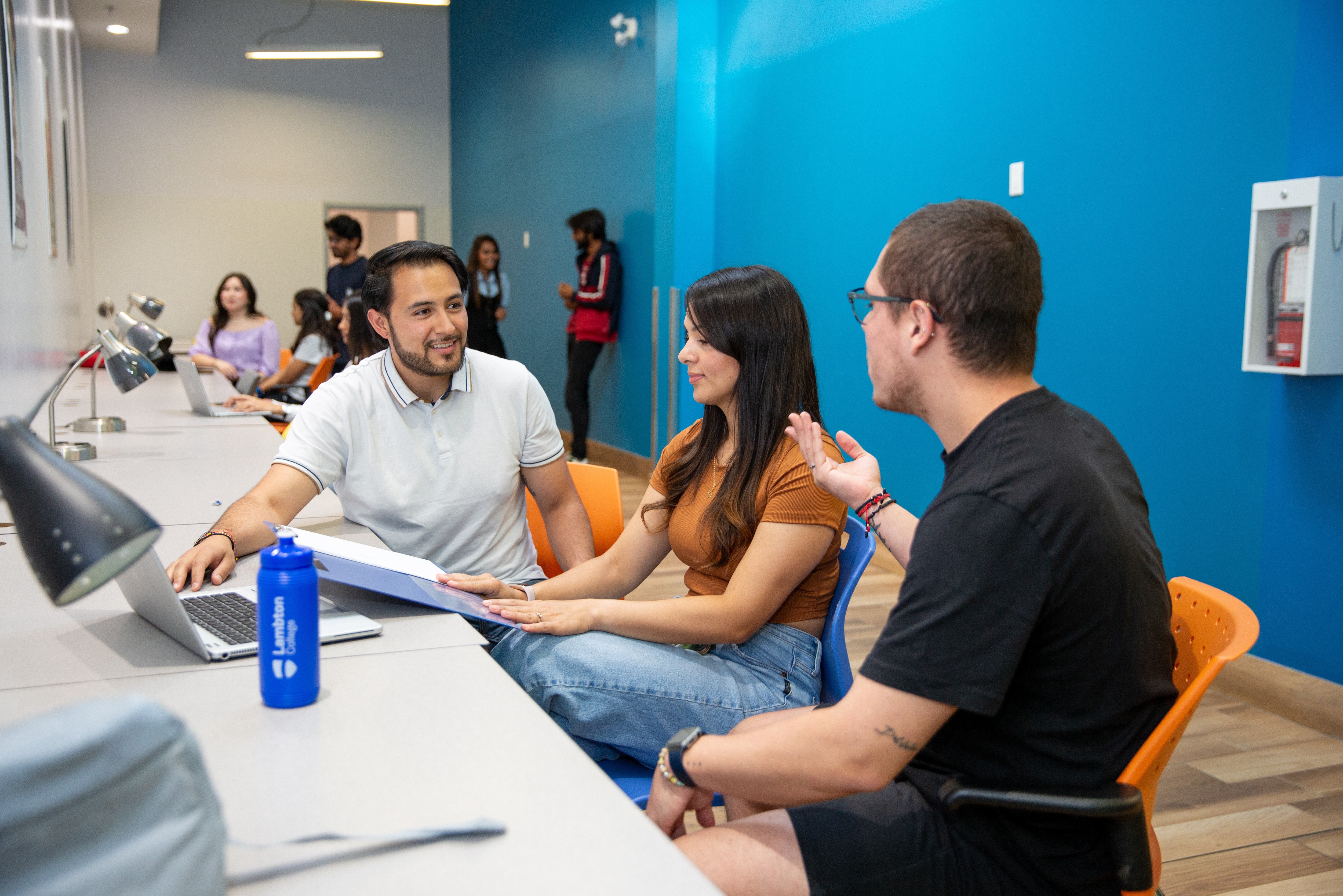 International students sitting at desk in hallway at the Lambton College Toronto campus.