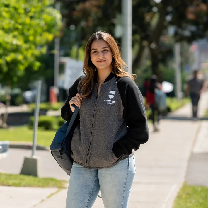 A student posing for photo on sidewalk.