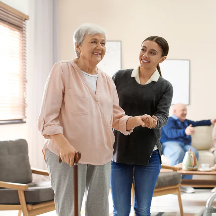 Student helping older patient walking in old age home.