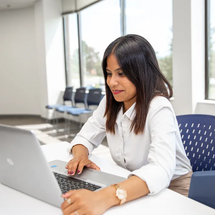 A student sitting at a desk using a laptop.