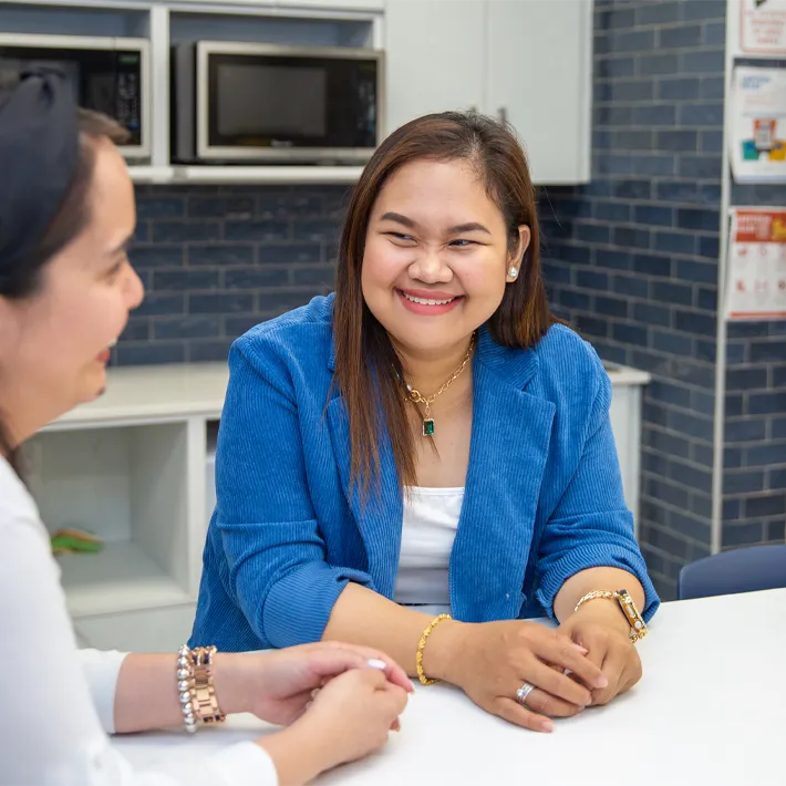 A photo of an international student sitting at a table smiling.