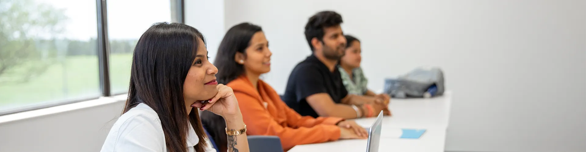 Students sitting in a classroom with books and laptops.