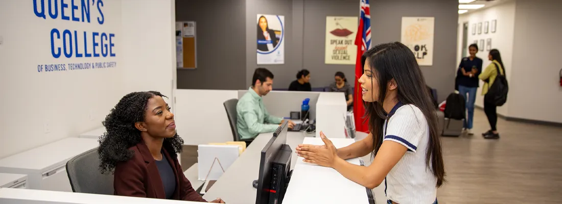 queens-international-lifestyle-student An international studend at the registrar office asking questions at the desk.