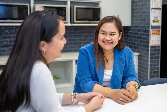 Two international students sitting at a high-top table in a common lounge area.