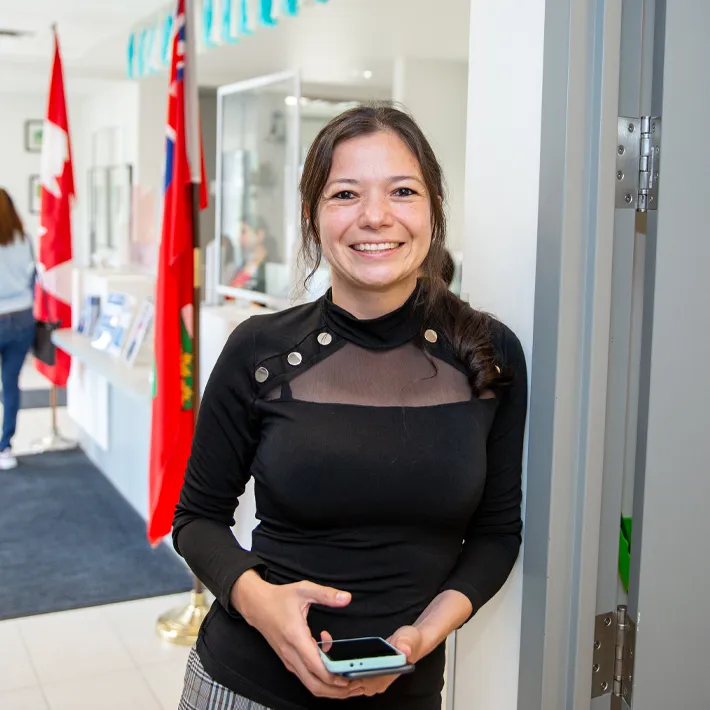 An international student posing for photo in hallways with flags in background.