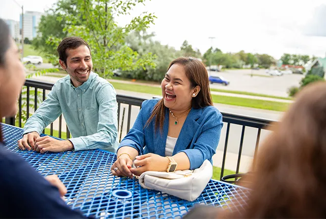A group of international students sitting at an outdoor picnic table on campus.