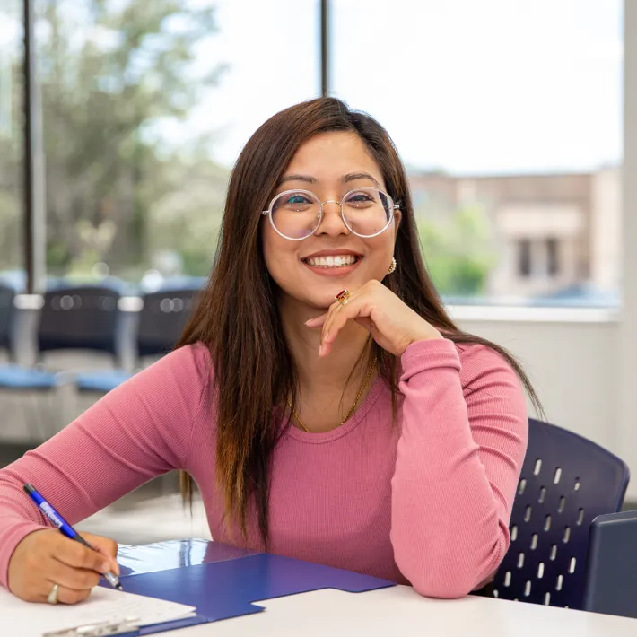 An international student sitting at a desk on Queens campus in Mississauga.