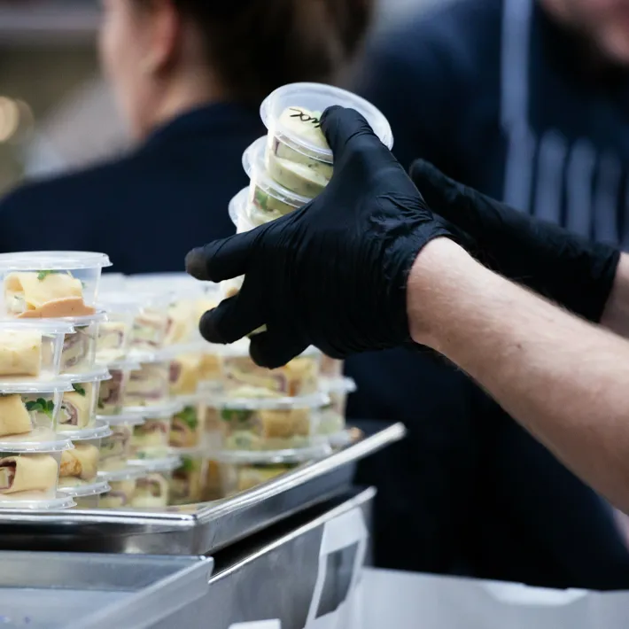 Food service worker sorting cups of food in a kitchen.