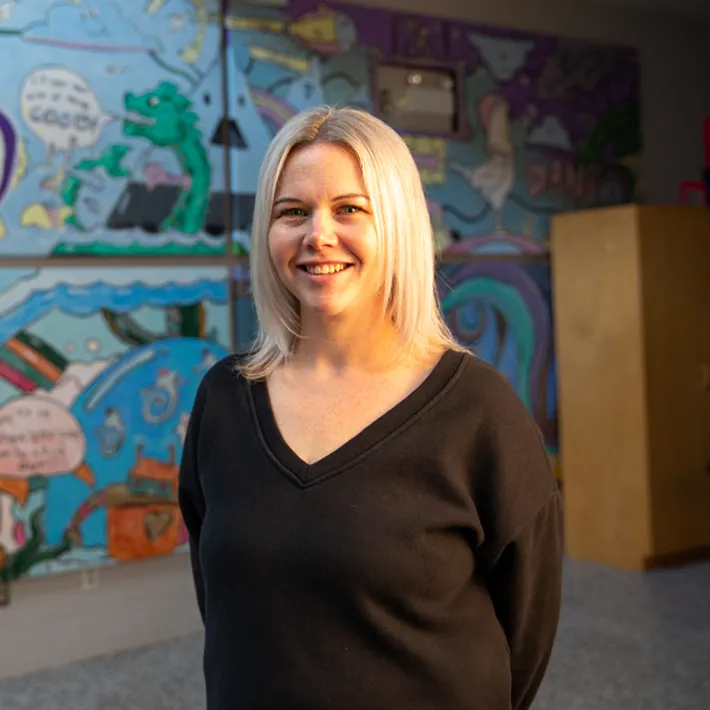 Big Borthers Big Sisters Executive Director posing for photo infront of grafiti wall.