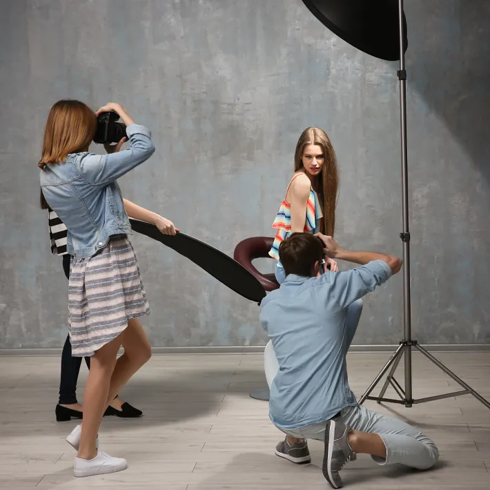 Photography students in studio taking photos of model.