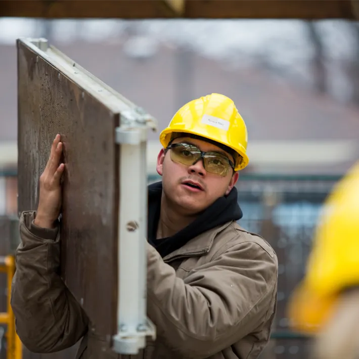 Construction student wearing hard hat working outside.