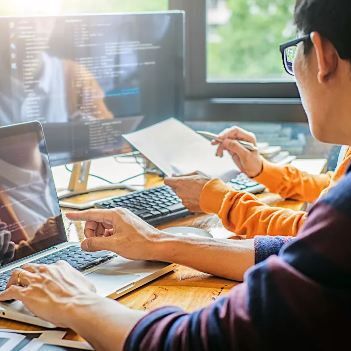 Two people looking at code on computer screens.