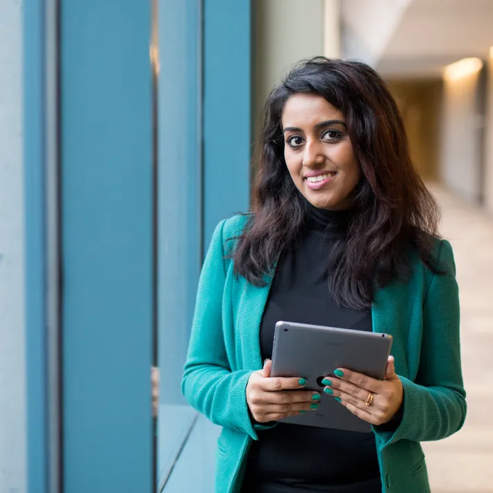 Business student holding ipad in hallway.