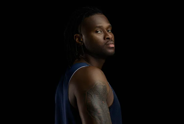 Photography student artistic photo of a basketball player posing in front of black background.