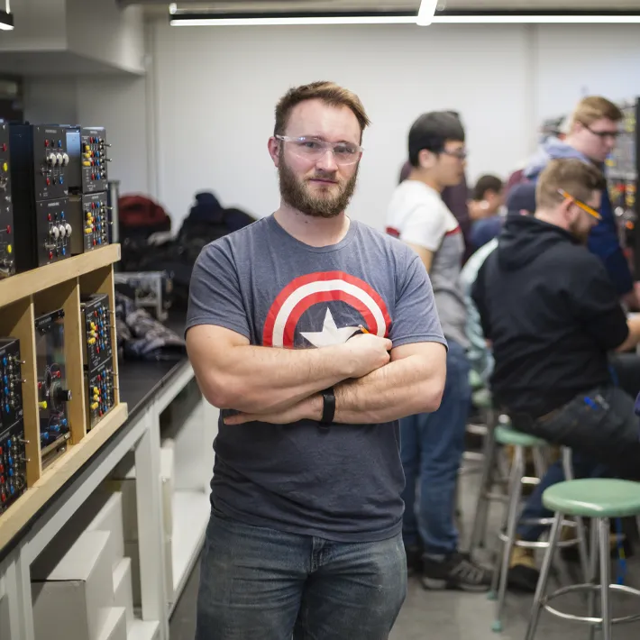 A student standing in electrical room with other students.