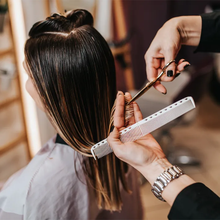 A hairsylist cutting hair in salon.