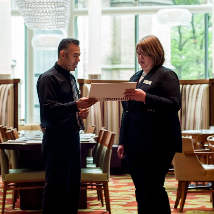 Hotel managers viewing pamphlet together in hotel lobby area.