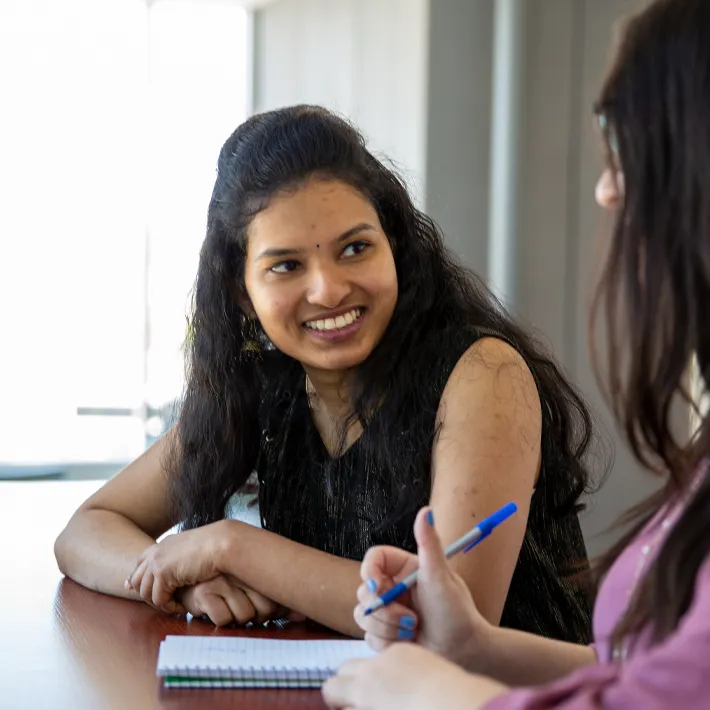 An international student smiling at desk on campus.